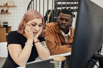 Worried businesswoman and businessman looking at computer monitor in office