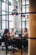 © Maskot - Full length of male and female colleagues discussing together in meeting room