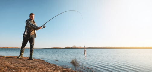 Wall Mural - Fisherman catching fish with rod at riverside, space for text. Banner design