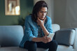 © nenetus - Shot of depressed woman using smartphone while sitting on the coach at home