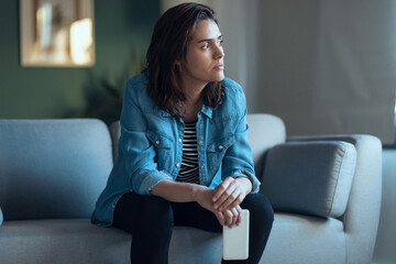 Depressed woman sitting on the coach at home