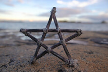 Pentagram Made Of Small Wood Sticks. Beach And Sea Horizon In The Background. Esoteric And Occult Concept. Mystic Rituals.
