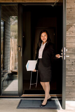 Portrait Of Smiling Real Estate Agent Opening Door At Entrance Of New House