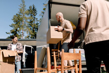 Delivery Company Employees Helping Man Unloading Boxes From Truck