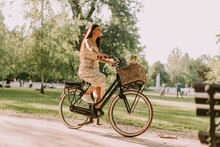 Young Woman Riding  Electric Bike With Flowers In The Basket