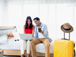 © tete_escape - Happy Asian couple, young man and woman looking and using laptop computer and smartphone together for flight booking and trip information in bedroom near baggage, travel on holiday, summer vacation.