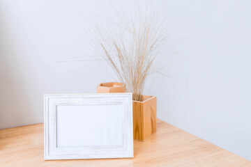 Wall Mural - Portrait white picture frame mockup on wooden table. Modern ceramic vase with eucalyptus. White wall background. Scandinavian interior. 