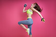 © gstockstudio - Confident young woman in sports clothing exercising against pink background