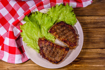 Wall Mural - Plate with roasted steaks and rosemary twigs on a wooden table. Top view