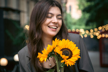 Canvas Print - Portrait of a young woman with a bouquet of sunflowers.