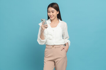 Wall Mural - Young beautiful asian woman with smart casual cloth use smartphone isolated on blue background