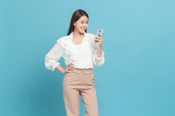 Wall Mural - Young beautiful asian woman with smart casual cloth use smartphone isolated on blue background