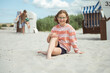 © spass - Happy girl sitting on white beach and brother on backround playing with ball at summer holidays