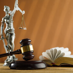 Wall Mural - On the table there is a wooden gavel of the judge, an open book and a bronze figurine of Themis on a beige background. Symbols of a fair trial, the rule of law. Banner, advertisement, poster.