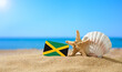 Tropical beach with seashells and Jamaica flag. The concept of a paradise vacation on the beaches of Jamaica.