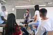 © EFStock - Teenager students listening and talking to friendly young male teacher - Group discussion in High School Education