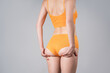 Skinny female buttocks in yellow panties on gray background, anti cellulite massage