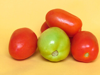 Wall Mural - Four ripe tomatoes, one green and yellow background