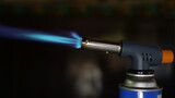 Fototapeta  - Close view of nozzle of a portable gas torch with dark backlit