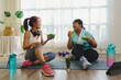 © KL 1981 - Fitness and Healthy food concept. Two Asian women body size is different in sportswear sitting smiling enjoys while eating healthy food together and happiness after fitness exercising at home.
