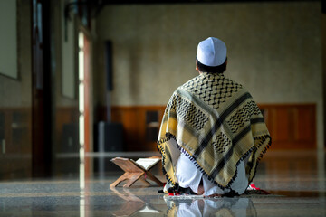 Wall Mural - A little Asian Muslim boy is praying with peace in the mosque, giving a powerful atmosphere of faith, with copy space.