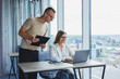 © Дмитрий Ткачук - A young woman at a laptop in glasses sits at a table, having a corporate business meeting with colleagues in a modern office. business career concept. Free space, selective focus