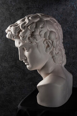 Gypsum copy of head statue David for artists on dark background. Replica of face famous sculpture youth of David by Michelangelo. Template design for art, dj, fashion, poster, zine. Renaissance epoch.