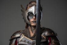 Antique Female Knight Dressed In Steel Armor Holding Sword Near Her Face.
