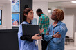 © DC Studio - African american woman and nurse looking at laptop to find recovery treatment for healthcare diagnosis in facility lobby. People talking about disease and medicine, using computer at reception.