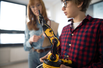 Wall Mural - college student presenting his builded robotic toy to young science teacher at robotics classroom at