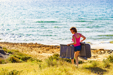 Canvas Print - Woman on beach carrying deckchair