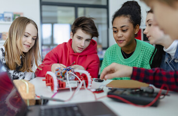 Wall Mural - group of high school students building and programming electric toys and robots at robotics classroo