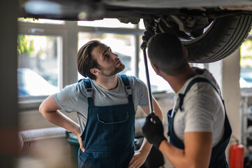 Auto workshop workers providing repair to the client car