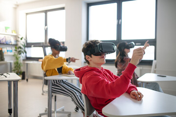 Wall Mural - teenage students wearing virtual reality goggles at school in computer science class