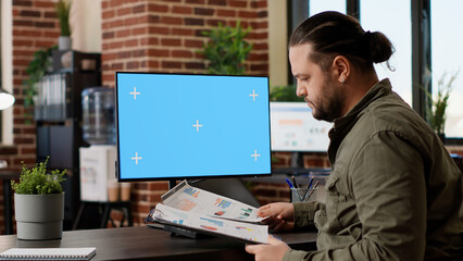 Wall Mural - company manager working with greenscreen mockup display on desktop computer, using blank copyspace t