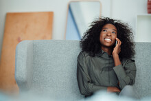 Happy Young Woman Talking Through Mobile Phone Sitting On Sofa