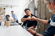 © Westend61 - Smiling businessman giving fist bump to colleague at workplace