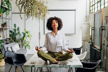 Young Businesswoman Meditating On Desk At Office