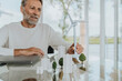 © Westend61 - Smiling mature man with wind turbine model sitting at table