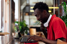 Smiling Man Typing On Laptop Sitting In Cafe