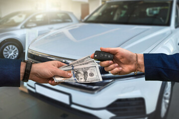 Wall Mural - man hands over a large sum of dollars to another who in return passes the keys to a car bought