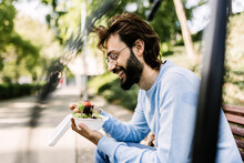 Smiling Bearded Man With Salad Sitting In Park