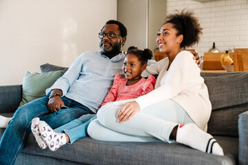 Wall Mural - African american family smiling and sitting on sofa at home