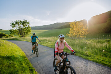 Wall Mural - Active senior couple riding electric bicycles on road at summer park, healthy lifestyle concept.