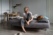 © DimaBerlin - Loneliness at midlife. Thoughtful sad middle-aged Scandinavian woman sitting on sofa with dog looking in distance, suffering from depression, feeling lonely, pondering what is the point of life