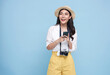 Happy young Asian tourist woman using smartphone application going to travel on holidays isolated on blue background.
