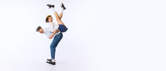 Wall Mural - Portrait of young cheerful couple, man and woman, in stylish retro outfit dancing isolated over white studio background. FLyer