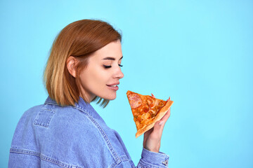 Wall Mural - young woman eating pizza slice and looking delighted