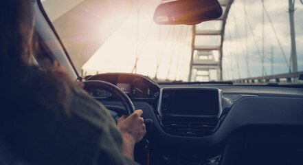 Woman driving a car, hands on the steering wheel, view of the control panel