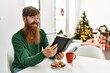 © Krakenimages.com - Young redhead man having breakfast sitting by christmas tree at home